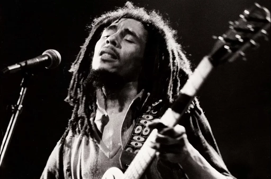 Bob Marley performing live on stage singing with his guitar
