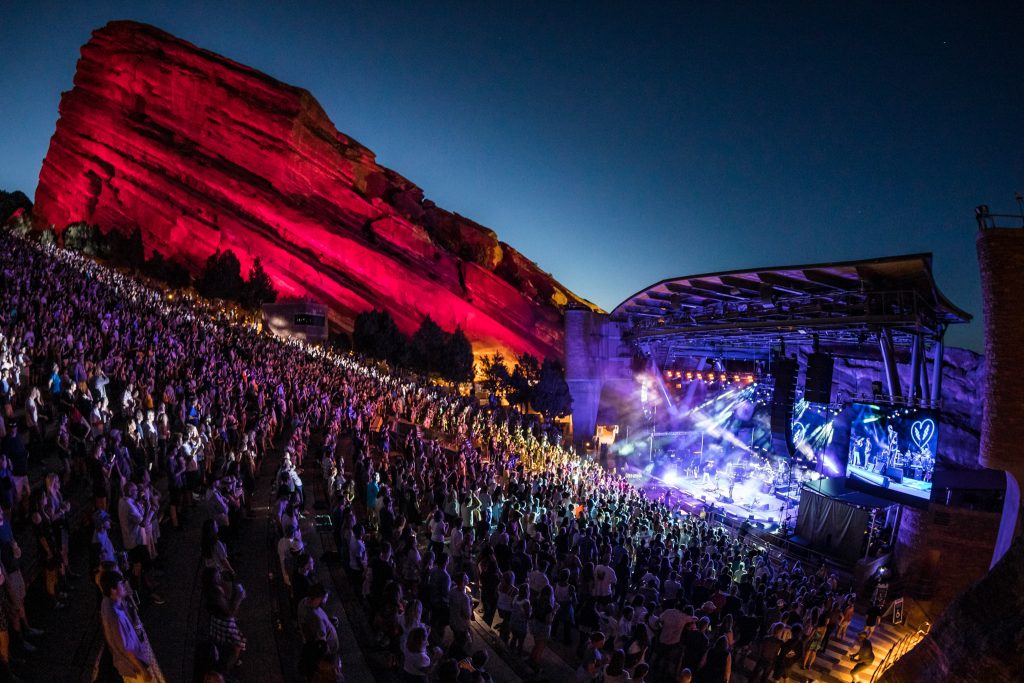 Red Rocks Ampitheatre with large crowd at night and light on the rock formations